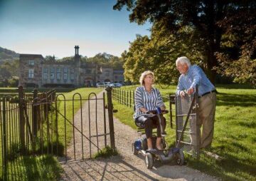 An elderly couple in their garden, lady on a mobility scooter