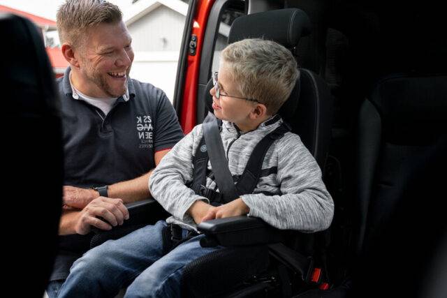 Can a carer drive a Motability car blog. Smiling dad with smiling son seated in car via the BraunAbility Carony system.