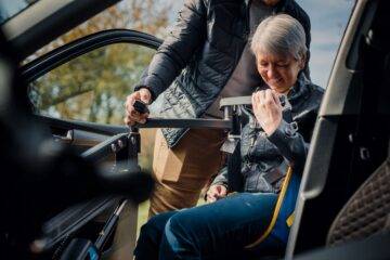 Passenger using Autochair person hoist to transfer in and of out her car