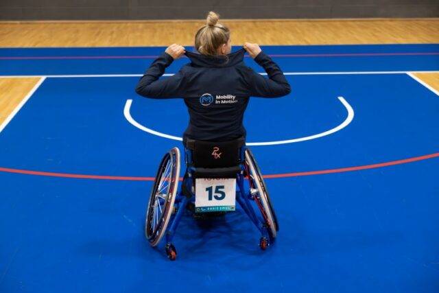 Robyn Love facing away from camera, posing in her sports wheelchair wearing Mobility in Motion jacket